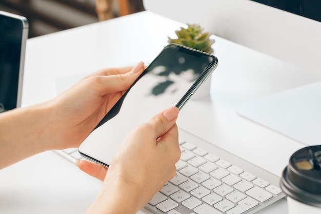 mani femminili facendo uso dello smartphone al tavolo dell'ufficio