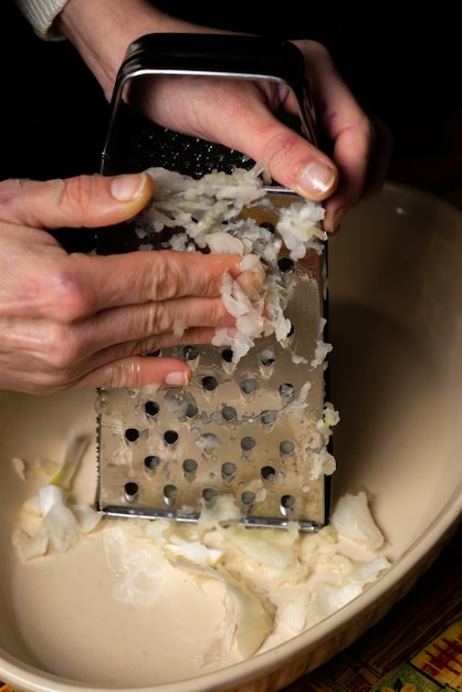 Mani femminili grattugiare la cipolla Preparare gli ingredienti per cucinare