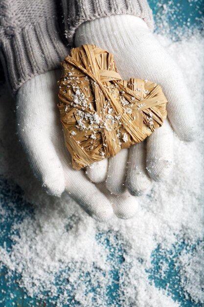 Mani femminili in guanti con cuore su sfondo di neve