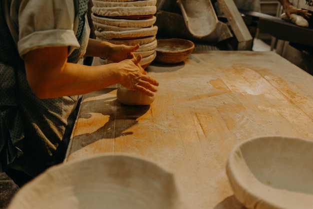 Mani femminili in primo piano della farina che impastano la pasta sul tavolo