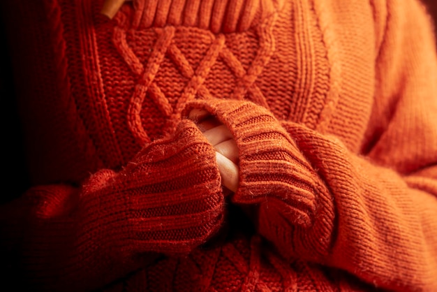Mani femminili in un caldo tema di calore del maglione