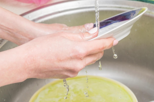 Mani femminili lavano i piatti Compiti in cucina Creazione di pulizia e ordine