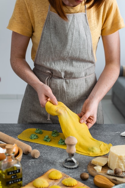 Mani femminili, processo di preparazione pasta italiana fatta in casa, ravioli