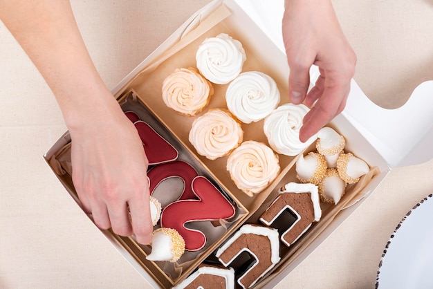 Mani femminili riempiono la scatola di Natale Marshmallow di panpepato nella scatola di Natale Prodotti da forno per le vacanze