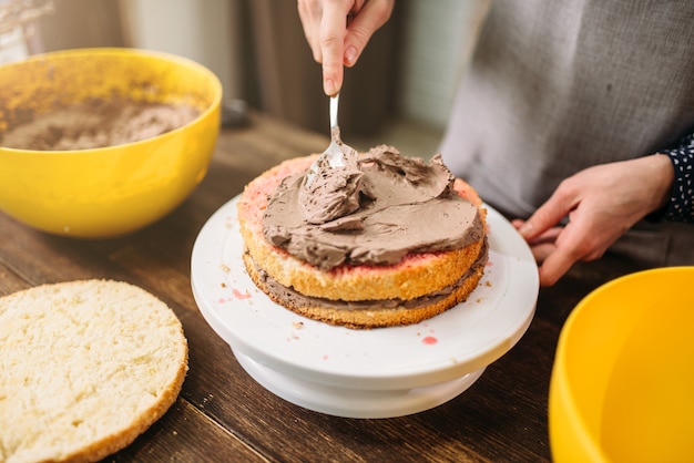 Mani femminili sbavature torta con vista del primo piano crema al cioccolato. Gustosi dessert fatti in casa