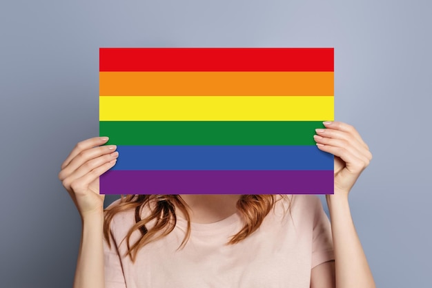 Mani femminili tengono una bolla di discorso con la comunità della bandiera LGBT isolata sullo sfondo blu