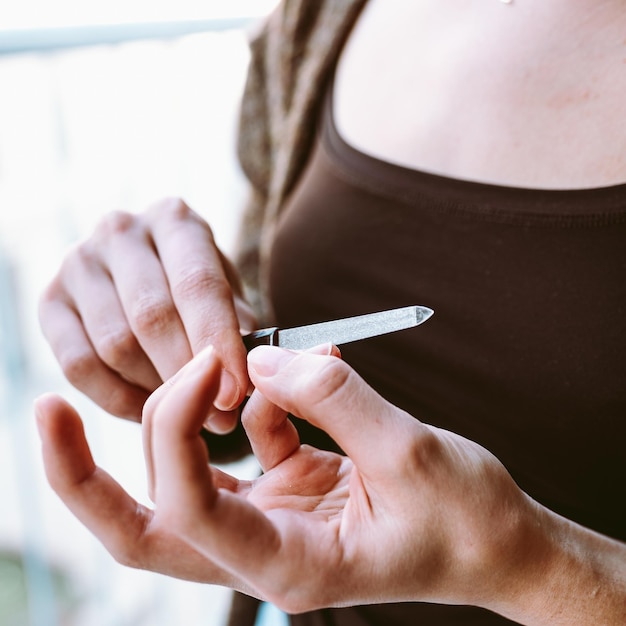 Mani giovane ragazza deposito chiodi Primo piano giovane donna con manicure tenendo la lima per unghie nelle mani