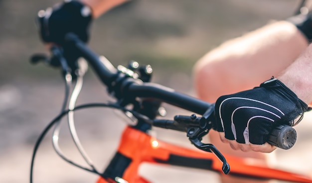 Mani in guanti sportivi sul manubrio della bici durante la corsa all'aperto