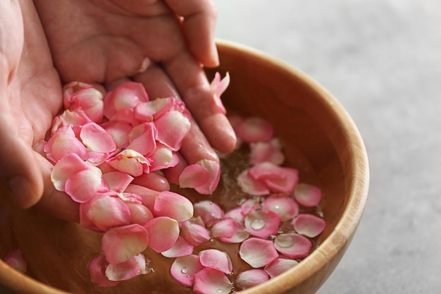 Mani in una ciotola di legno con petali e acqua