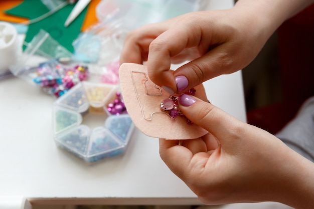 Mani, la donna fa la decorazione della spilla con perline rosa e cristalli
