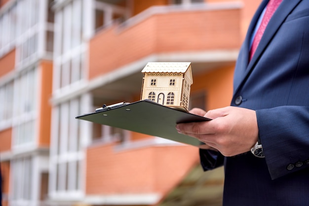 Mani maschii con appunti e modello di casa in legno da vicino