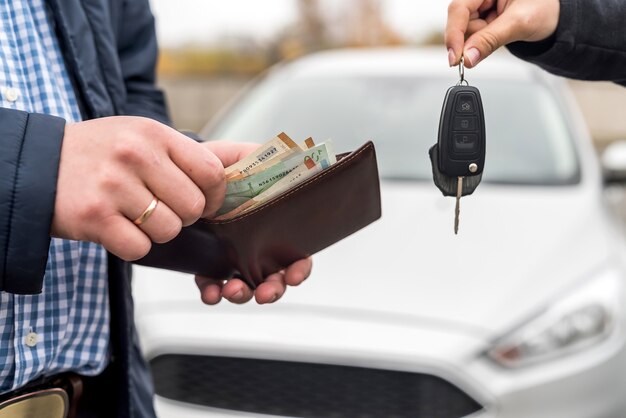 Mani maschii con portafoglio e mani femminili con chiavi dall'auto