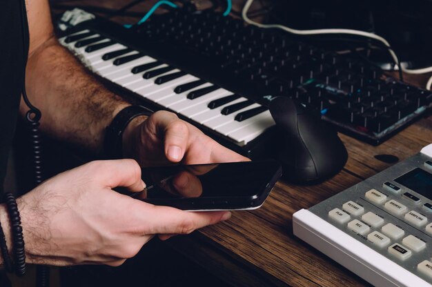 Mani maschili caucasiche che utilizzano un telefono in uno studio domestico che invia messaggi
