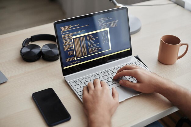 Mani maschili che digitano sulla tastiera del portatile e scrivono codici