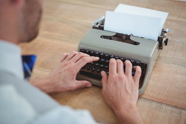 mani maschili che digitano sulla vecchia macchina da scrivere sul tavolo di legno