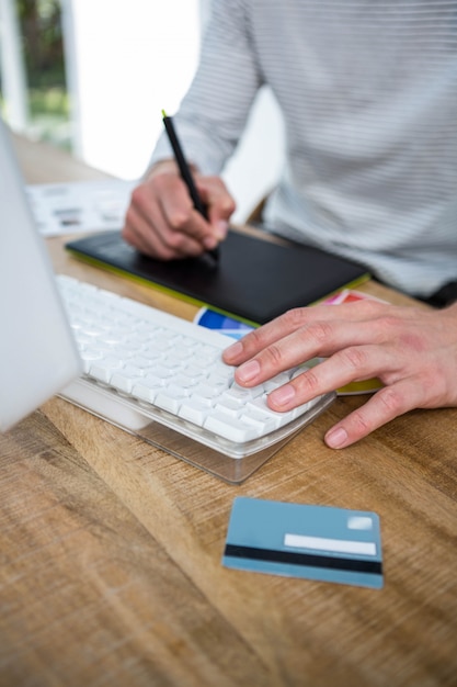 Mani maschili che prendono le note e che scrivono sulla tastiera in un ufficio luminoso