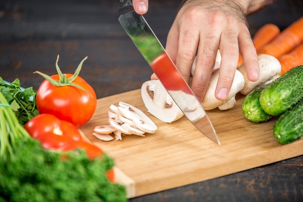 Mani maschili che tagliano verdure per insalata