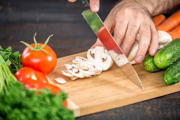 Mani maschili che tagliano verdure per insalata