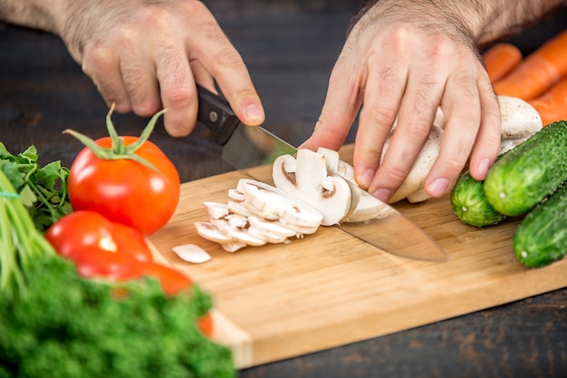 Mani maschili che tagliano verdure per insalata