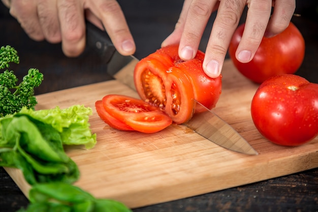 Mani maschili che tagliano verdure per insalata