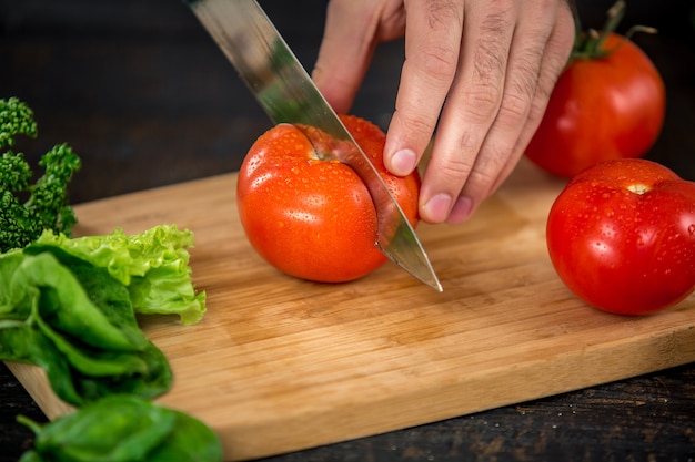 Mani maschili che tagliano verdure per insalata