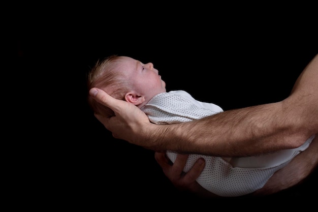 Mani maschili che tengono un bambino Neonato che dorme Sfondo nero Vista laterale isolata