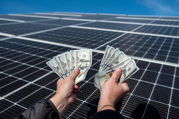 Mani maschili con banconote da un dollaro sullo sfondo della natura dove ci sono pannelli solari