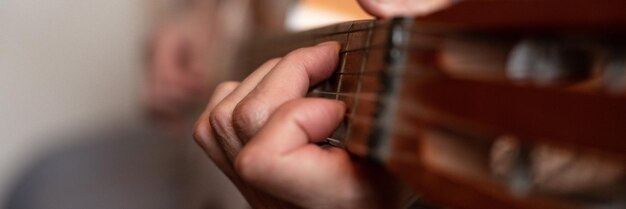 Mani maschili di un anziano uomo caucasico anziano che tiene e suona una chitarra classica da vicino a casa chitarrista senza volto non professionale la gente suona musica amatoriale hobby domestici e banner per il tempo libero