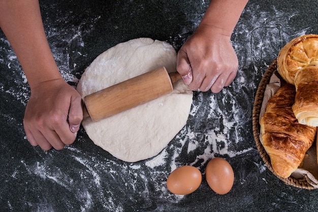 Mani maschili impastare la pasta cosparsa di tavolo di farina