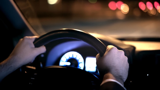 Mani maschili sul sedile posteriore del volante con vista sulla strada di notte