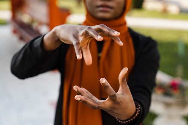 Mani ravvicinate di donna musulmana nera alla meditazione cinese di qigong e all'allenamento sportivo all'aperto. La ragazza africana sta meditando all'aperto vicino al pergolato cinese.