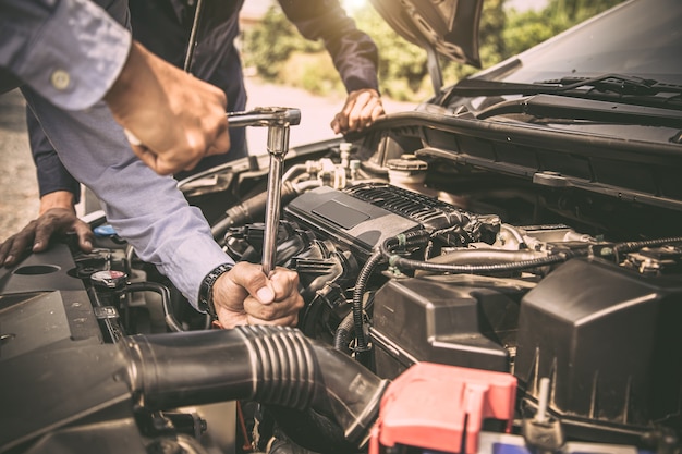 Mani ravvicinate di un meccanico che utilizza la chiave per la manutenzione del motore dell'auto.