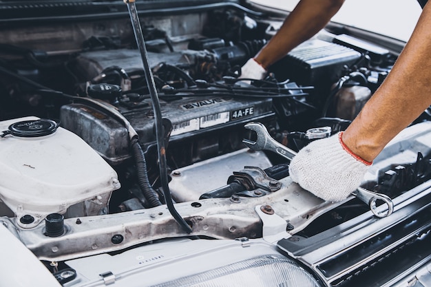 Mani ravvicinate di un meccanico che utilizza la chiave per la manutenzione del motore dell'auto.