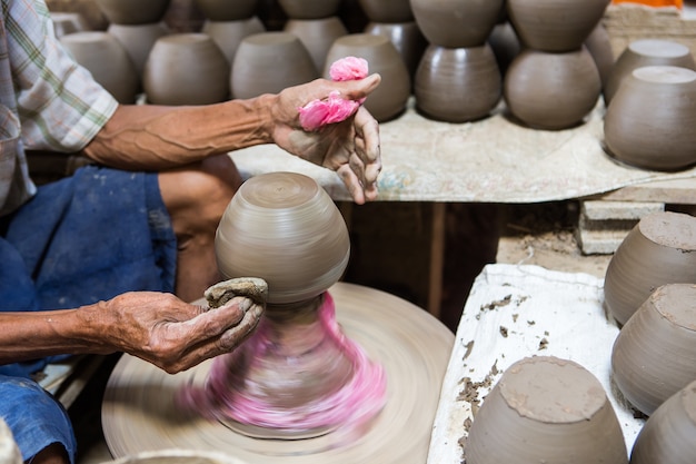 mani sporche che producono ceramiche in argilla sulla ruota