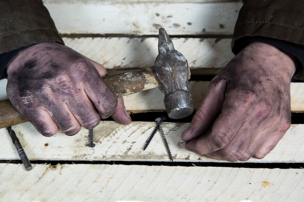 Mani sporche di lavoratori con strumenti martelli e chiodi.