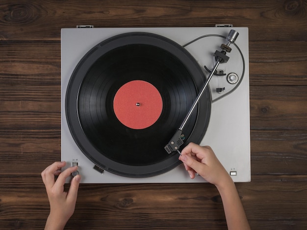 Mani sui giradischi in vinile su uno sfondo di legno