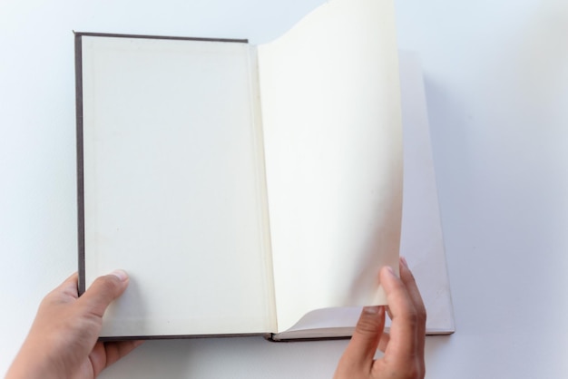 Mani tagliate che aprono un libro su uno sfondo bianco