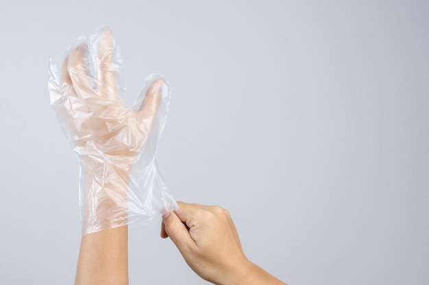 Mani tagliate che indossano un guanto di plastica su uno sfondo grigio
