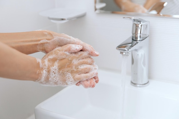 Mani tagliate che si lavano le mani nel lavandino