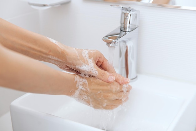 Mani tagliate che si lavano le mani nel lavandino