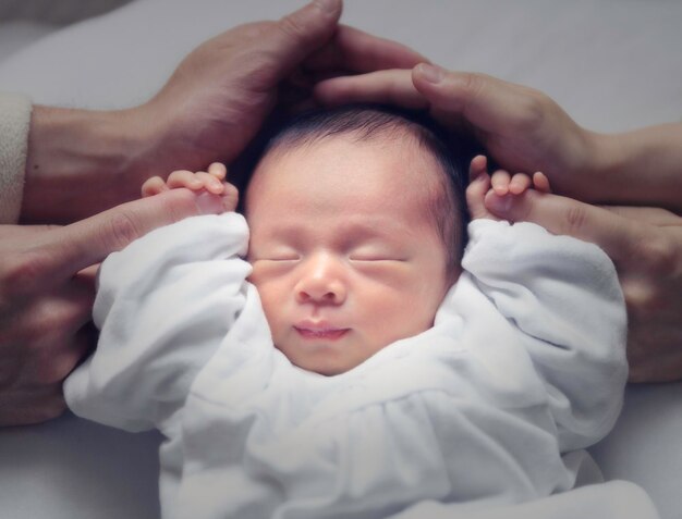 Mani tagliate da persone con un bambino sdraiato sul letto a casa