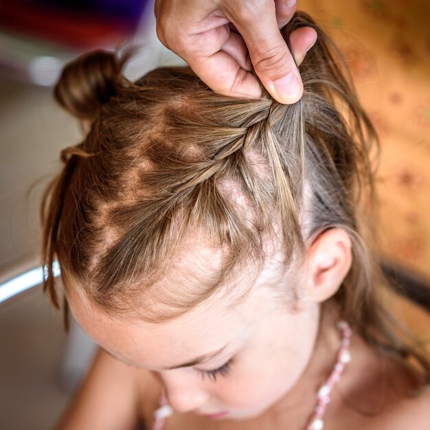 Mani tagliate di madre che intreccia i capelli della figlia
