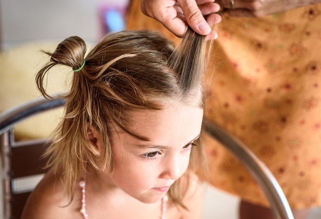 Mani tagliate di madre che lega i capelli della figlia