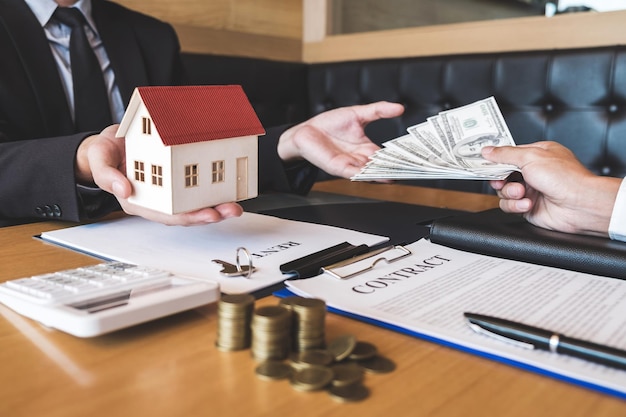 Mani tagliate di un acquirente che dà soldi a un agente alla scrivania dell'ufficio