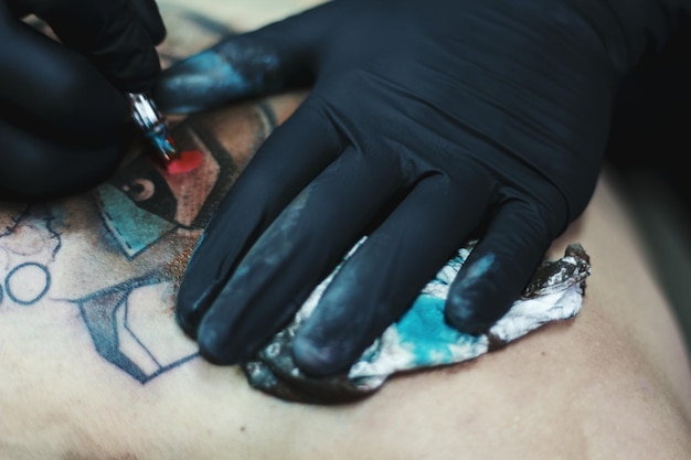 Mani tagliate di un artista maschio che fa un tatuaggio su un cliente