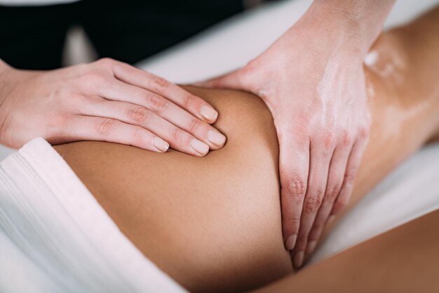 Mani tagliate di un massaggiatore che massaggia una cliente femminile in una spa