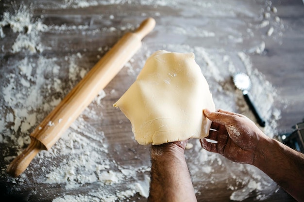 Mani tagliate di un uomo che prepara la pasta su tavola