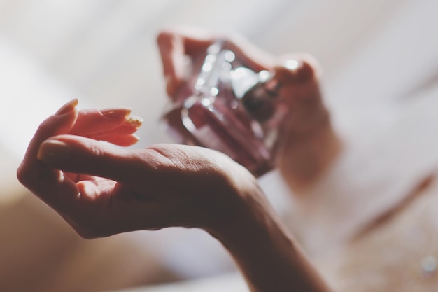 Mani tagliate di una donna che applica profumo