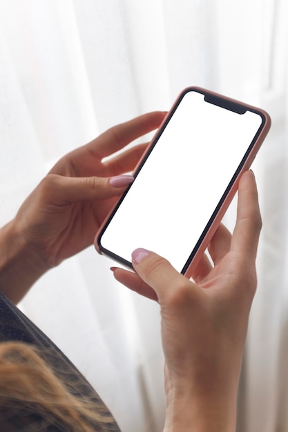 Mani tagliate di una donna che usa il telefono cellulare a casa