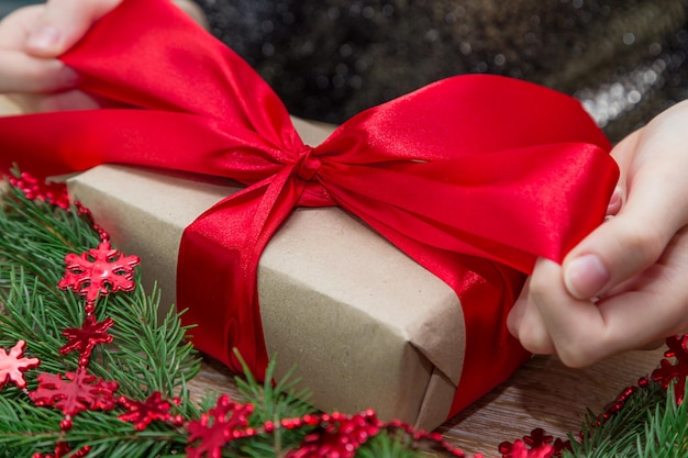 Mani tagliate di una donna con un regalo di Natale sul tavolo